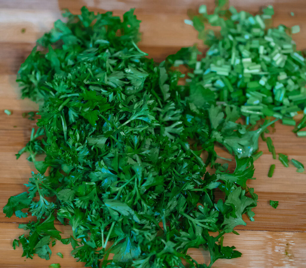 Parsley leaves and chopped parsley stems on the chopping board