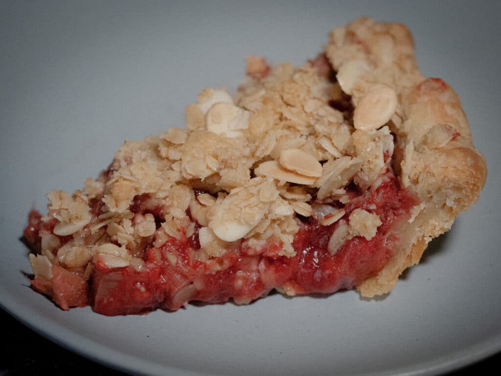 A slice of strawberry-rhubarb crisp on a light blue dessert plate